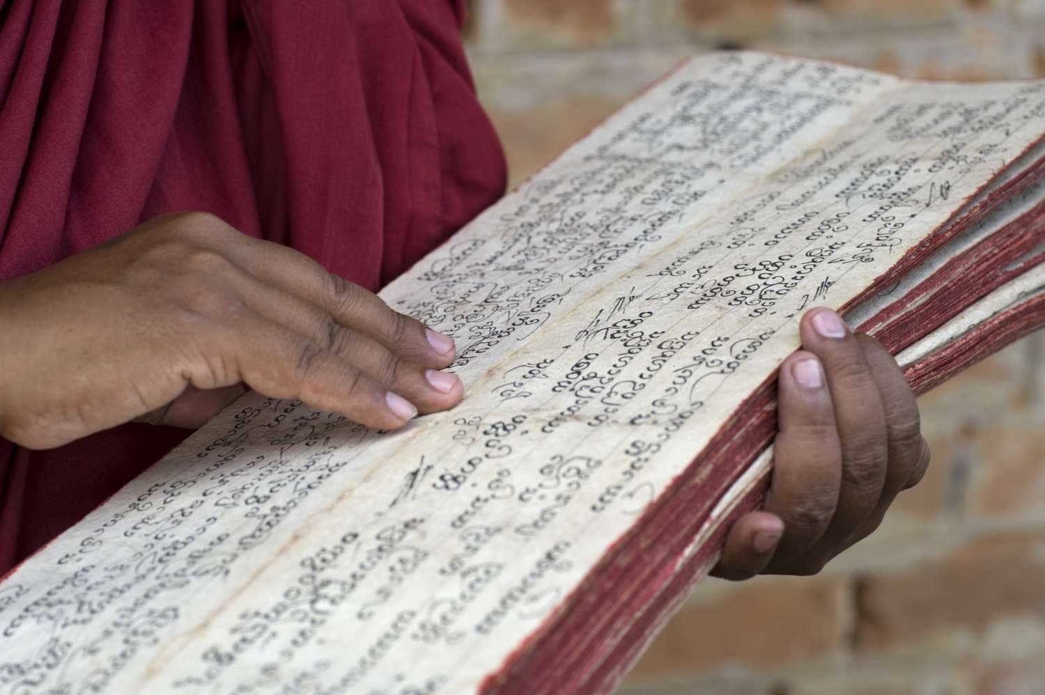A close view of a Buddhist manuscript held in warm light.